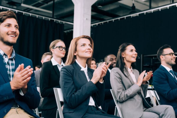 Smiling multiethnic businesspeople applauding during business seminar in conference hall